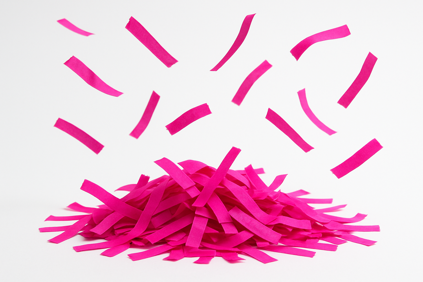 hot pink confetti strips in a pile with some floating
