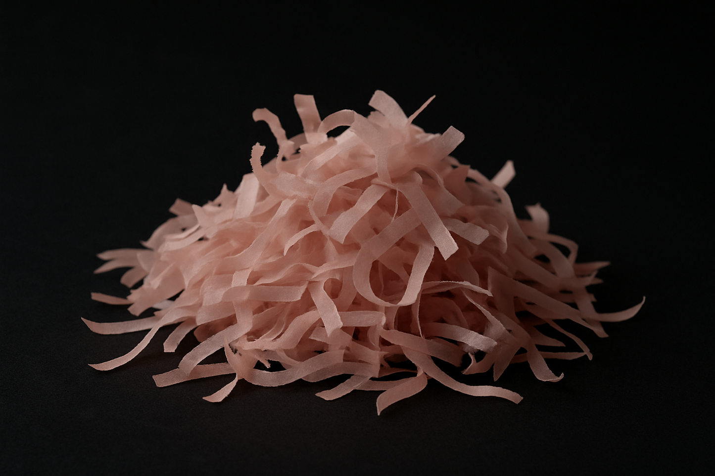 dust pink confetti strips in a pile with dark background